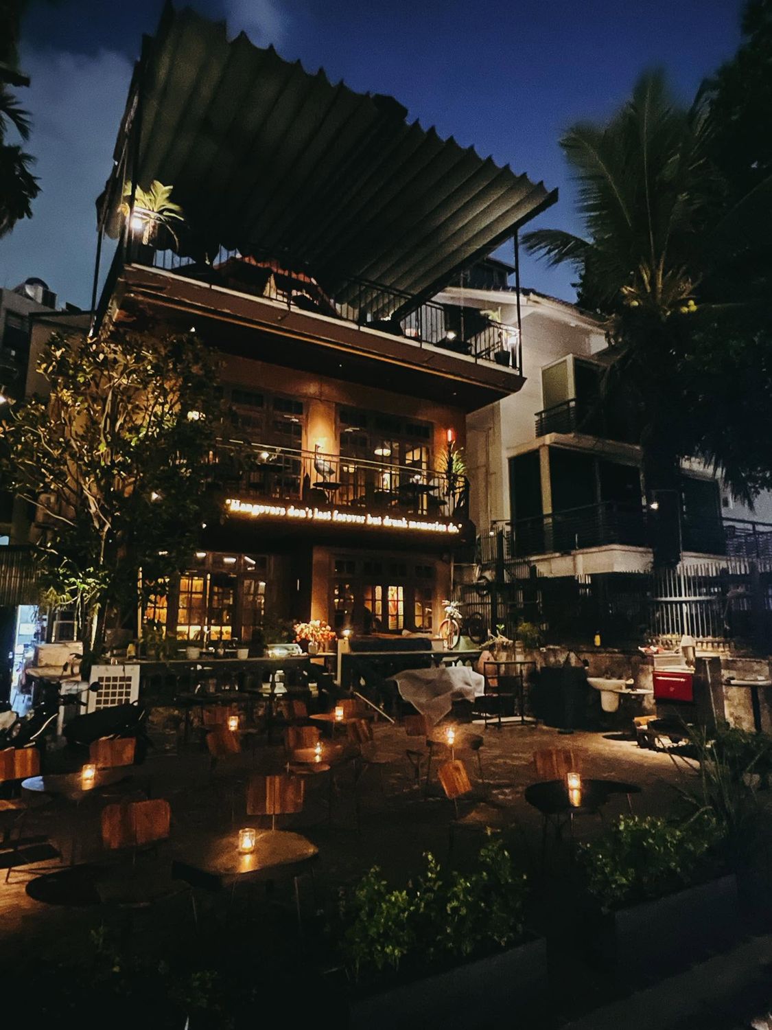 The house lit at night above the garden