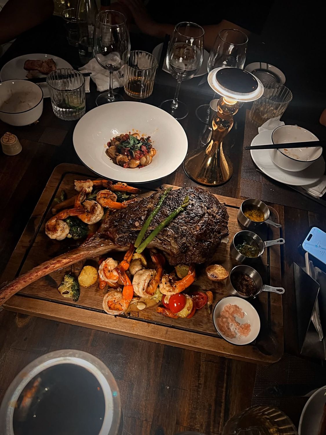 Dry-aged tomahawk with grilled prawns on a wooden board
