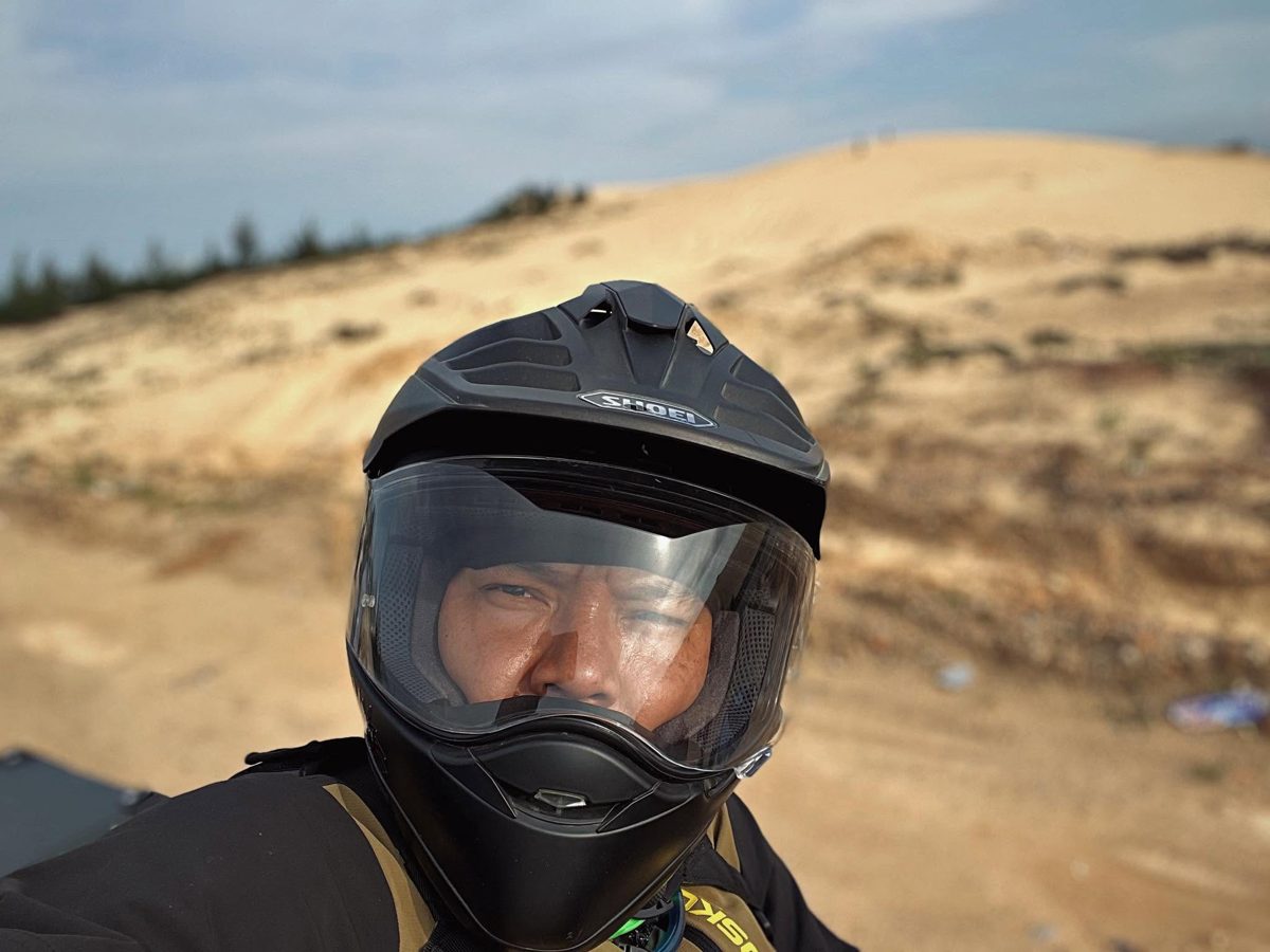Loija in a riding helmet in front of sand dunes