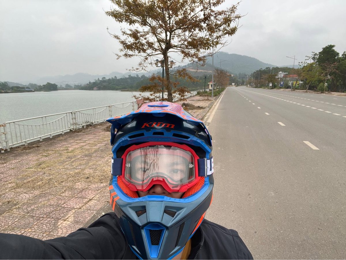 Loija in a motocross helmet beside a lake road