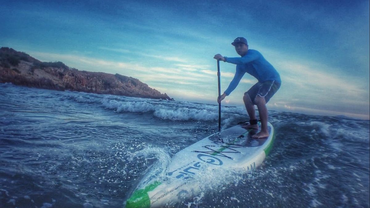 Loija paddleboarding through waves at dusk