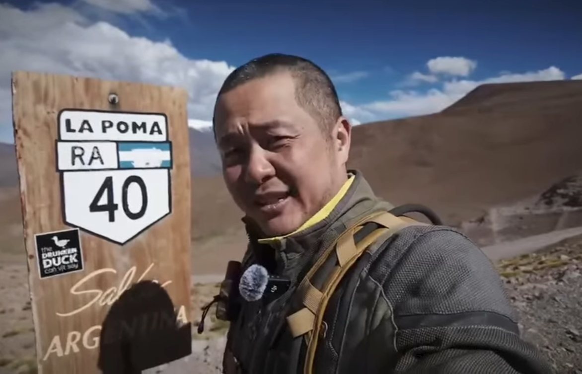 Huy beside a Ruta 40 La Poma sign in the Argentine mountains, a Drunken Duck sticker on the sign