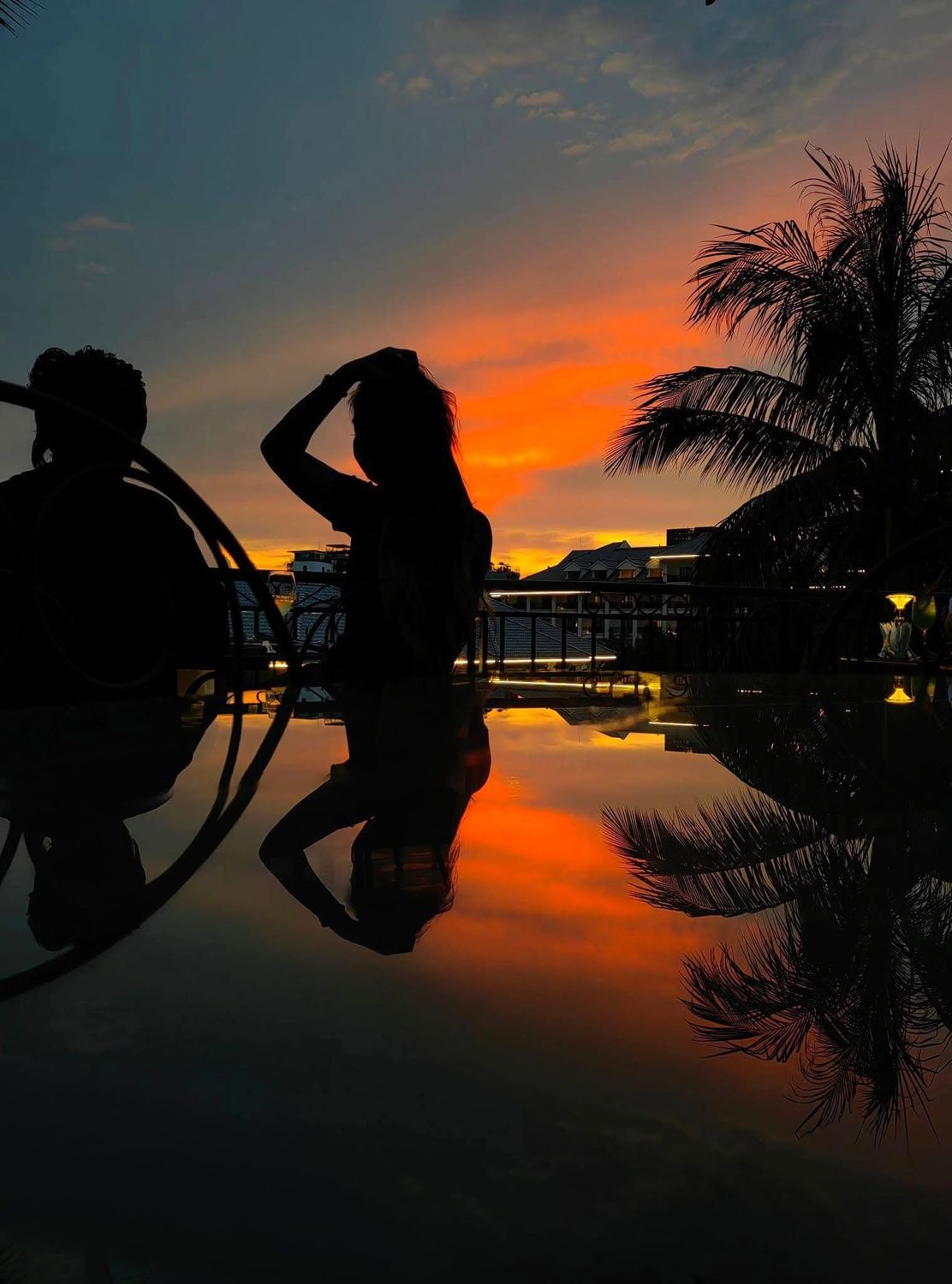 Two guests silhouetted against the sunset on the balcony